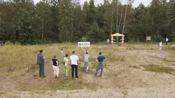 СЕНТ-ПЕТЕРБУРГ, РОССИЯ - 30 июля 2016 года: Вид с воздуха на людей, сбивающих плюши гигантской рогаткой на краю леса — стоковое видео