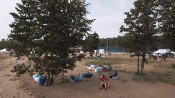 Sankt Petersburg, Ryssland - 30 juli 2016: Antenn sköt personer handpåläggning beanbags under träden på sandiga stranden sommartid — Stockvideo