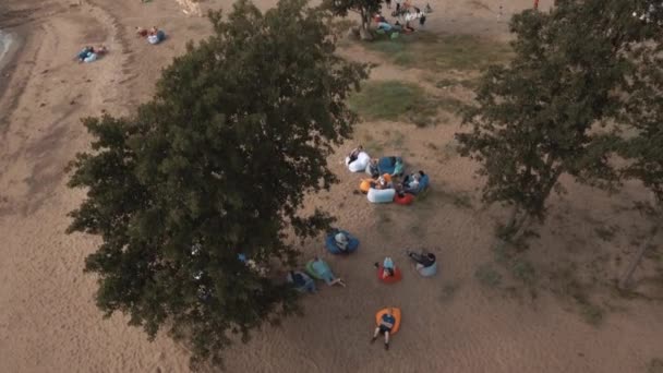 SAINT PETERSBURG, RÚSSIA - JULHO 30, 2016: Vista aérea pessoas deitadas em sacos de feijão sob árvores na costa arenosa no verão — Vídeo de Stock