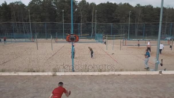 SAINT PETERSBURG, RÚSSIA - JULHO 30, 2016: Homem esportivo tiro aéreo jogando basquete na areia coberta praia campo de esportes — Vídeo de Stock