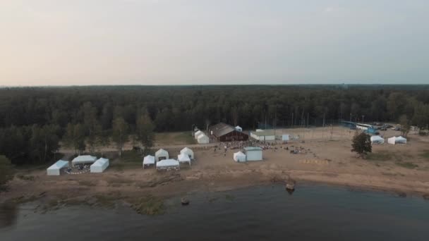 Sint-Petersburg, Rusland - 30 juli 2016: Luchtfoto shot zand strand in de buurt van bos met witte tenten en sport gemalen in de zonsondergang — Stockvideo