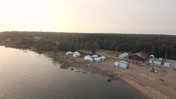 Sint-Petersburg, Rusland - 30 juli 2016: Luchtfoto zand strand in de buurt van bos met witte tenten en sport gemalen in de zonsondergang — Stockvideo