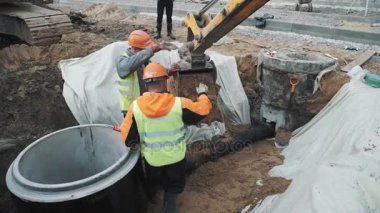 Saint Petersburg, Rusya - 26 Eylül 2016: İşçilerin zor şapka müşteri adayları ekskavatör kum hendekte plastik boru üzerine damping