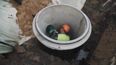Saint Petersburg, Rusya - 26 Eylül 2016: İşçisi kask plastik boru üzerinde dolgu macunu kullanarak beton kuyu halka içinde