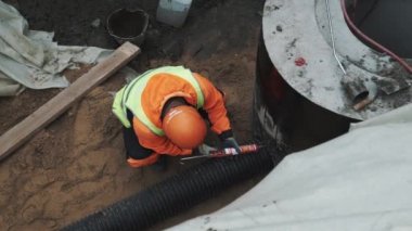 Saint Petersburg, Rusya - 26 Eylül 2016: İşçisi kask kullanım dolgu macunu hendekte beton kuyu ringde plastik boru