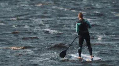 Saint Petersburg, Rusya Federasyonu - 28 Ağustos 2016: ihtimal sporcu tam mayo bir raket kullanarak sörf tahtası rides