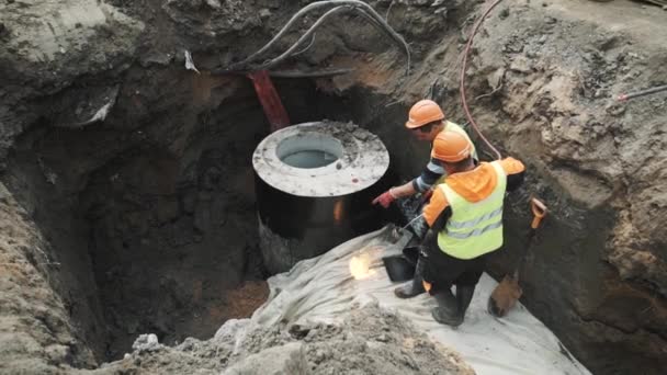 SAN PETERSBURG, RUSIA - 26 DE SEPTIEMBRE DE 2016: Trabajadores en sombreros duros arden el anillo de alcantarilla de la cámara de hormigón con lanzallamas — Vídeos de Stock