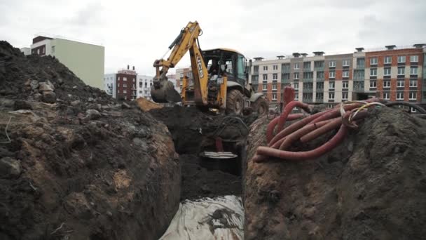 SAN PETERSBURG, RUSIA - 26 DE SEPTIEMBRE DE 2016: La excavadora excavadora de cámara lenta arroja tierra a una zanja de alcantarillado en el sitio de construcción — Vídeo de stock