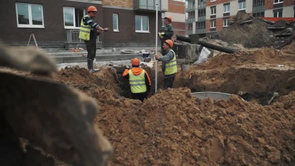 Sint-Petersburg, Rusland - 26 September 2016: Slowmotion werknemers in oranje veiligheidshelmen praten in de sloot op de bouwplaats — Stockvideo