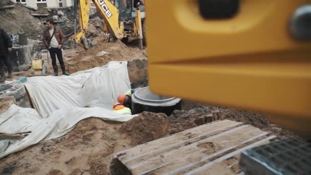 SAINT PETERSBURG, RUSSIE - 26 SEPTEMBRE 2016 : Travailleurs à mouvement lent portant des casques durs dans un fossé avec des matériaux en tissu sur le chantier — Video