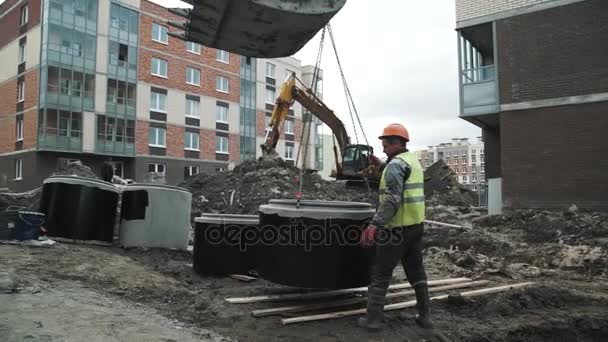 Sint-Petersburg, Rusland - 26 September 2016: Slowmotion Rookvrije werknemer lood graafmachine te hangen van de concrete mangat ring op kettingen — Stockvideo