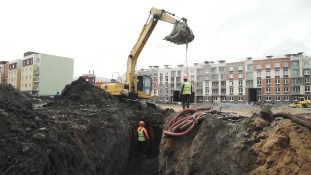 SAINT PETERSBURG, RÚSSIA - SETEMBRO 26, 2016: Trabalhadores abaixando anel de bueiro de concreto da panela da escavadeira para baixo da vala — Vídeo de Stock