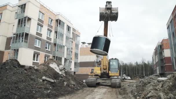 Petrohrad, Rusko - 26 září 2016: Bagr jednotky při budování webu s kroužkem betonové šachty houpání na pánvi — Stock video
