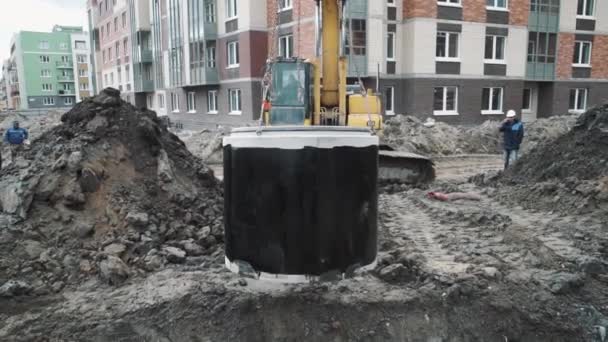 SAN PETERSBURG, RUSIA - 26 DE SEPTIEMBRE DE 2016: Anillo de cámara de alcantarillado de hormigón colgado en cucharón de excavadora que baja a la zanja — Vídeo de stock