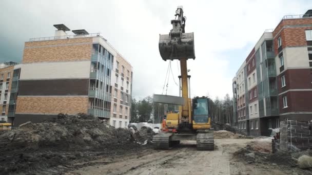 Saint Petersburg, Rusya - 26 Eylül 2016: Sarı Ekskavatör taşımaları site oluşturma, zincirleri beton kuyu halkası üzerinde. — Stok video
