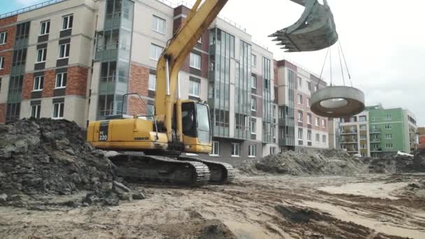 SAINT PETERSBURG, RUSSIE - 26 SEPTEMBRE 2016 : Une pelle jaune porte une bague de trou d'homme en béton sur le chantier . — Video