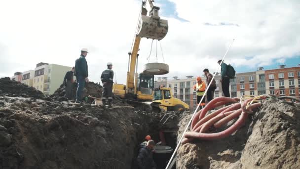 SAN PETERSBURG, RUSIA - 26 DE SEPTIEMBRE DE 2016: Excavadora con anillo de alcantarilla de hormigón en cadenas llega a zanja en obra — Vídeos de Stock