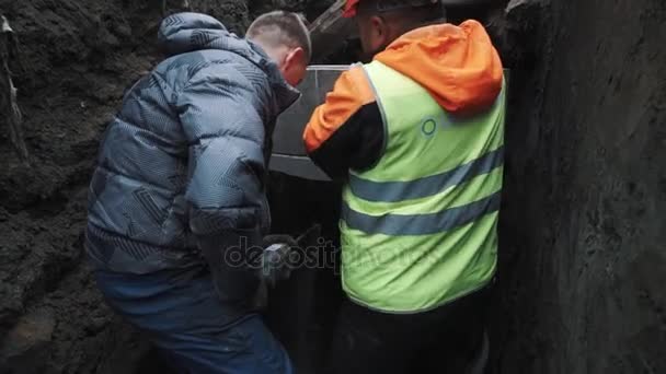 Sint-Petersburg, Rusland - 26 September 2016: Man en builder boren gat in concrete kamer mangat ring in sloot — Stockvideo