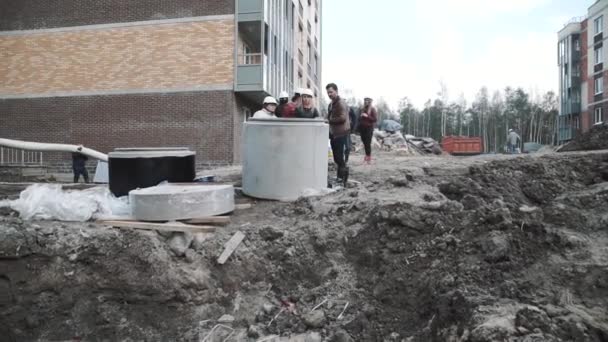 SAINT PETERSBURG, RÚSSIA - 26 de setembro de 2016: Homem diz às mulheres em chapéus duros sobre anel de bueiro de câmara de concreto no canteiro de obras — Vídeo de Stock