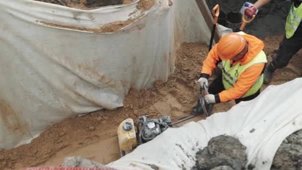 SAINT PETERSBURG, RÚSSIA - SETEMBRO 26, 2016: Compactador de placa de uso do construtor na areia na trincheira coberta com material de pano branco — Vídeo de Stock