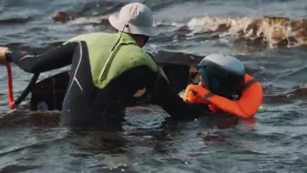 Sint-Petersburg, Rusland - 28 augustus 2016: Man in zwembroek helpt een jongen in zwemvest om te leren hoe om te rijden op een wakeboard — Stockvideo