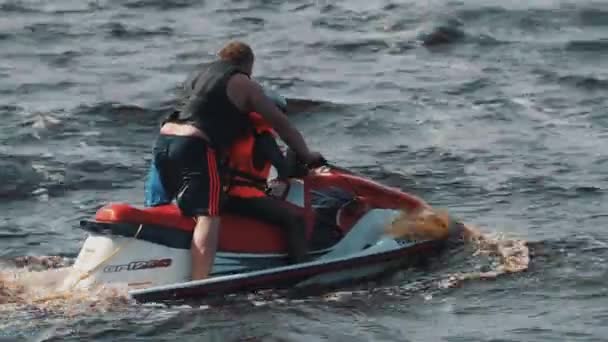 俄罗斯圣彼得堡-2016 年 8 月 28 日︰ 男子在救生衣和头盔，橙色背心骑摩托艇在高速上的男孩 — 图库视频影像