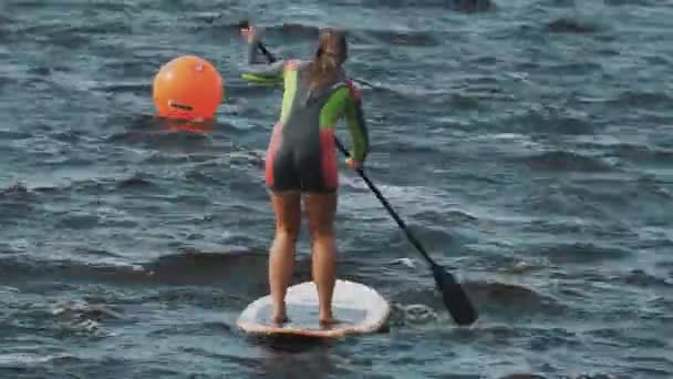 SAINT PETERSBURG, RÚSSIA - AGOSTO 28, 2016: Longo tiro de mulheres em bandejas tremidas maiô completo para montar uma prancha de surf usando remo — Vídeo de Stock