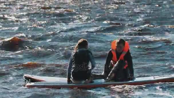 САЙНТ-ПЕТЕРБУРГ, РОССИЯ - 28 августа 2016 года: Сёрфбордист пытается встать на доску для сёрфинга, но падает в воду — стоковое видео