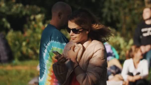 Saint petersburg, russland - 28. august 2016: junge frau mit smartphone draußen im park während sommerveranstaltung. viele Menschen — Stockvideo