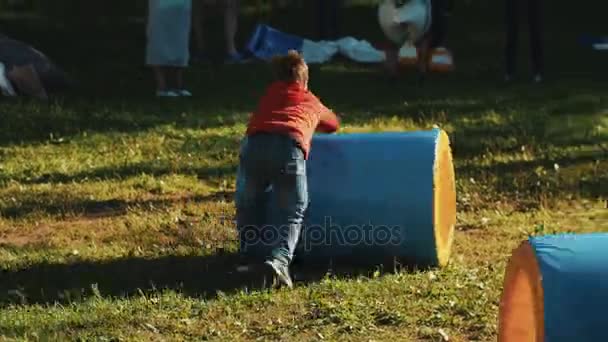 SAINT PETERSBURG, RUSSIA - 28 AGOSTO 2016: I bambini si corrono a vicenda facendo rotolare un tubo gonfiato sull'erba fuori — Video Stock
