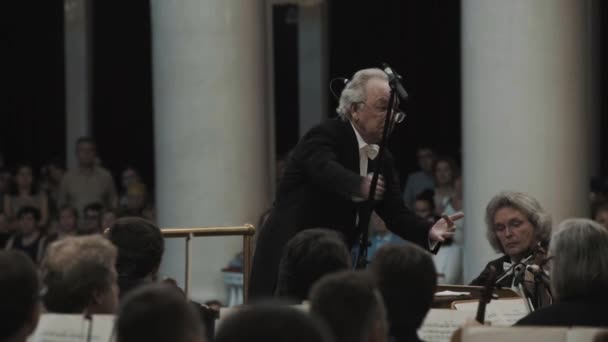 SAINT PETERSBURG, RUSSIA - JUNHO 23, 2016: Maestro de cabelos brancos dirigindo orquestra de cordas na sala de concertos de estilo clássico — Vídeo de Stock