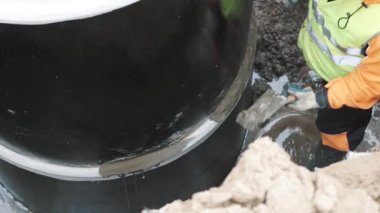 Saint Petersburg, Rusya Federasyonu - 26 Eylül 2016: Çimento macun bıçak ile iki beton kuyu halkalar arasında işçi mühür dikiş