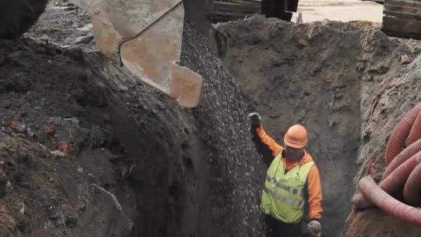 Sankt Petersburg, Ryssland - 26 September 2016: Arbetare i orange hård hatt ledande bulldozer dumpning breakstone i att dike — Stockvideo