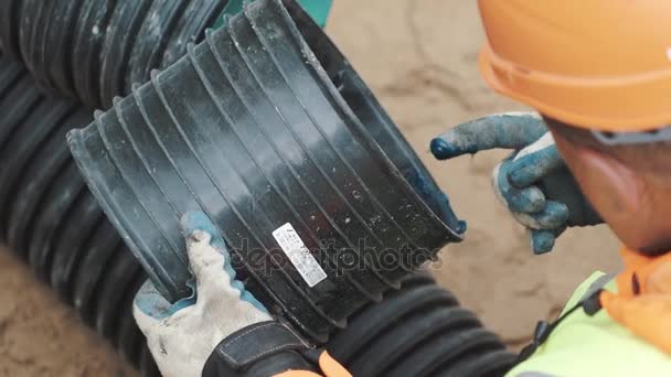 SAN PETERSBURG, RUSIA - 26 DE SEPTIEMBRE DE 2016: Constructor en duro tenía la aplicación de gel azul con el dedo en el borde de la tubería de plástico negro — Vídeo de stock