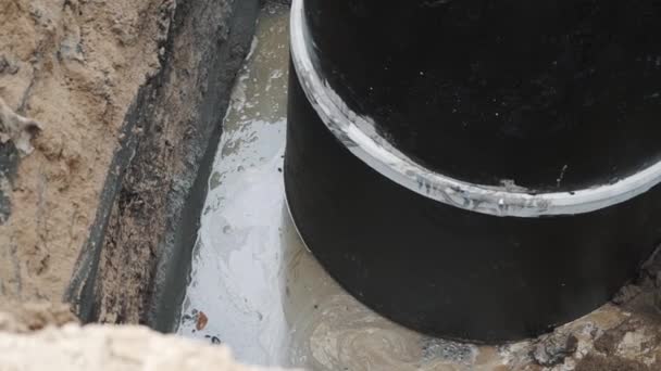 SAN PETERSBURG, RUSIA - 26 DE SEPTIEMBRE DE 2016: Agua turbia y suciedad alrededor de un anillo de alcantarilla de hormigón en una zanja de arena en el sitio de construcción — Vídeo de stock