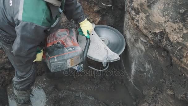 Saint petersburg, russland - 26. september 2016: bauarbeiter mit kreissäge schneidet betonkonstruktion im graben auf baustelle — Stockvideo