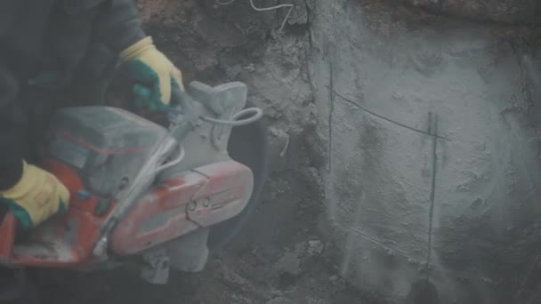 SAINT PETERSBURG, RUSSIA - SEPTEMBER 26, 2016: Lots of dust and fug producing by builder circular saw concrete in dirt ditch. — Stock Video