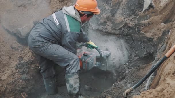 Saint petersburg, russland - 26. september 2016: bauer mit kreissäge schneidet betonkonstruktion im graben auf baustelle — Stockvideo