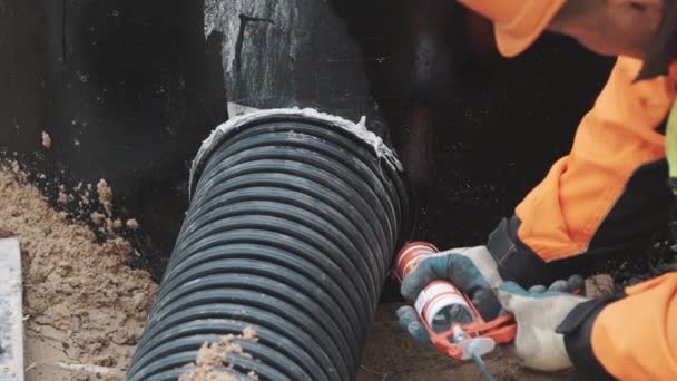 Saint petersburg, russland - september 26, 2016: bauer setzt dichtmittel auf fuge zwischen geripptem kunststoffrohr und betonloch — Stockvideo