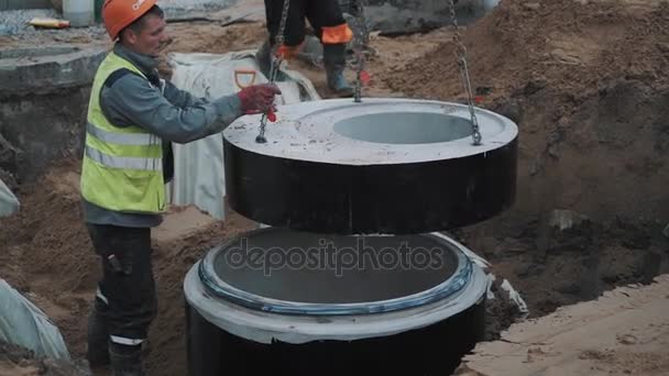 労働者が建設現場で下水道の構造の上にコンクリート製マンホール リングを置くサンクトペテルブルク, ロシア連邦 - 2016 年 9 月 26 日。 — ストック動画