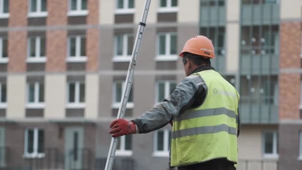 SAINT PETERSBURG, RUSSIE - 26 SEPTEMBRE 2016 : Travailleur en casque orange fumant sur le chantier, tenant une longue règle en métal — Video