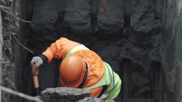 俄罗斯圣彼得堡-2016 年 9 月 26 日︰ 生成器在橙色安全帽用铲建筑工地上挖土沟 — 图库视频影像