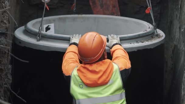 SAINT PETERSBURG, RUSSIA - 26 SETTEMBRE 2016: Lavoratore in cappello rigido che tira anello tombino camera di cemento su catene in fosso — Video Stock