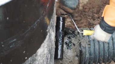 İşçi el tar siyah plastik boru ve beton arasında çimento dikiş koymak
