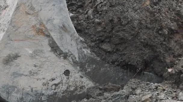 Balde escavadora de câmera lenta puxando placa de concreto sob pilha de solo e sujeira — Vídeo de Stock