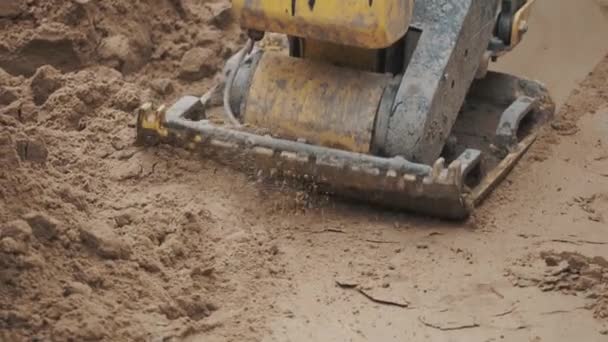 Lento movimento trabalhando gazolina placa amarela compactador espessamento superfície de areia — Vídeo de Stock