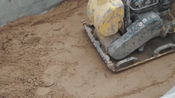 Slowmotion arbetande bensin gul vibroplatta komprimera sand ytan — Stockvideo