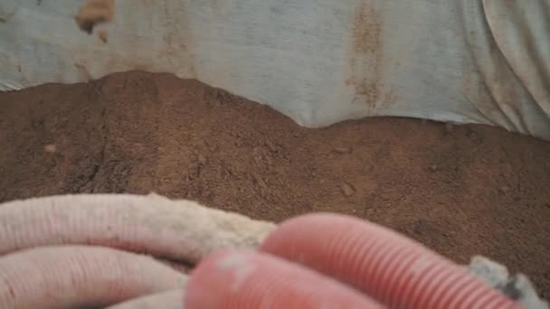 Slowmotion sand regn i dike täckt av tyg med svarta och röda plaströr — Stockvideo