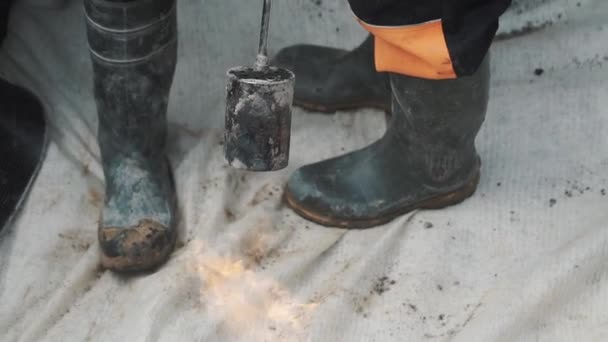 Torche à gaz flamboyante brûlant matériau en tissu blanc avec deux paires de bottes en caoutchouc sur — Video