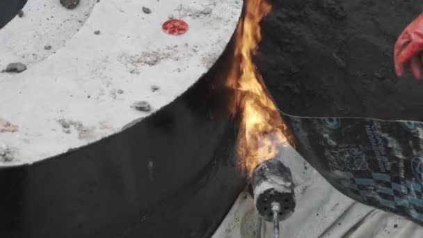 Los constructores queman una tira de goma negra para pegarla al hormigón en la zanja. Lento. — Vídeo de stock